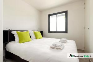 een slaapkamer met een groot wit bed met groene kussens bij Ventoux Ride in Malaucène