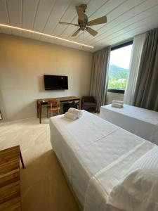 a bedroom with two beds and a flat screen tv at Pousada Yamandu in Juquei