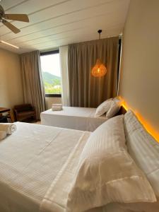 2 Betten in einem Hotelzimmer mit Fenster in der Unterkunft Pousada Yamandu in Juquei