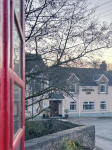 Czerwona budka telefoniczna przed białym budynkiem w obiekcie Penybont Restaurant + Inn w mieście Carmarthen