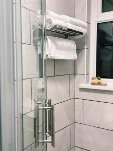 a bathroom with a glass shower door with towels at Penybont Restaurant + Inn in Carmarthen