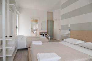 a white bedroom with two beds and a bathroom at Hotel Leon D'oro in Cattolica +71 photos