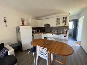 eine Küche mit einem Holztisch mit Stühlen und einem Kühlschrank in der Unterkunft Appartement vue lac - 6304 in Hourtin