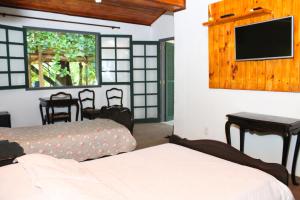 a bedroom with two beds and a flat screen tv at Fazenda Dos Coqueiros-Bananal-SP in Bananal