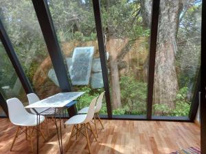 Habitación con mesa, sillas y ventana grande. en Casa inmersa en el Bosque en San Carlos de Bariloche