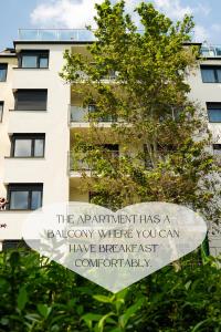 a sign in front of a building with a tree at Mátyás Corner Apartments Green Square Studio Apartment II in Budapest