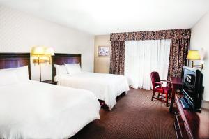 a hotel room with two beds and a television at Clifton Victoria Inn at the Falls in Niagara Falls