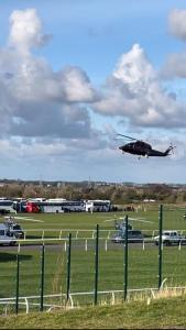 een helikopter vliegt over een veld met auto's bij Aintree Grand National Home in Aintree