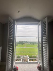 een open raam met uitzicht op een groen veld bij Aintree Grand National Home in Aintree