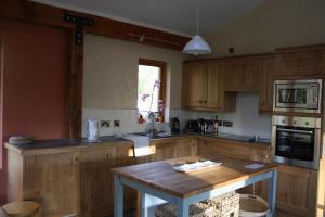 a kitchen with wooden cabinets and a wooden table at Hemp Cottage in Crossgar