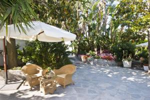 une terrasse avec des chaises, un parasol et une table dans l'établissement Hotel San Francesco, à Ischia