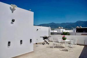 eine Terrasse mit einem Tisch und Stühlen auf einem Gebäude in der Unterkunft La casa de los colibríes in Hacienda Blanca