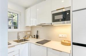 a white kitchen with a sink and a microwave at Can Estrellas, appartement d'exception sur la mer in Roses