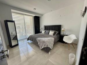 ein Schlafzimmer mit einem Bett, einem Spiegel und einem Stuhl in der Unterkunft La casa de los colibríes in Hacienda Blanca