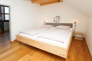 a bedroom with a bed with white sheets and wooden floors at Wendlingen Ferienwohnung 3 in Freiburg im Breisgau