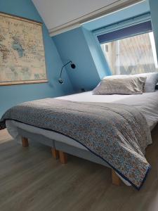 een slaapkamer met een bed met een blauwe muur bij Le Flamand in Saint-Omer