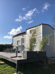 ein Haus mit einer Terrasse mit Stühlen davor in der Unterkunft Tiny house à la ferme près Paris et center parcs. in Boissy-sur-Damville