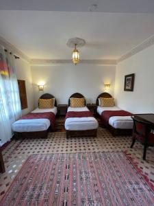 a room with four beds and a rug at Riad Dar Laura in Fès