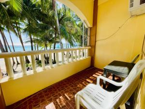 uma varanda com cadeiras brancas e uma mesa e o oceano em LA FIESTA RESORT em Boracay