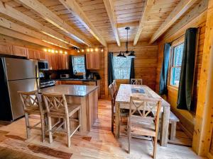 a kitchen with a table and chairs in a cabin at 65PT New Log Cabin in Private Setting. Hot tub. Gym/Pool Access! in Twin Mountain