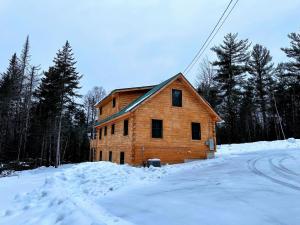 a wooden house in the snow on a road at 65PT New Log Cabin in Private Setting. Hot tub. Gym/Pool Access! in Twin Mountain