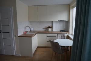 a small kitchen with white cabinets and a table at Studio Anna in Panevėžys