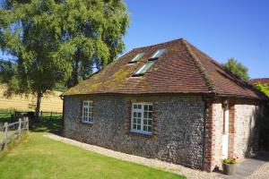 a small brick building with windows and a roof at Luxury barn with tennis court in South Downs National Park in Chichester