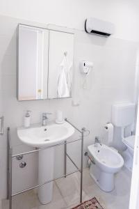 uma casa de banho branca com um lavatório e um WC em CasaRiso em Grammichele