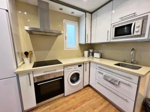 een keuken met witte kasten en een wasmachine en droger bij Precioso y céntrico apartamento de playa in Fuengirola