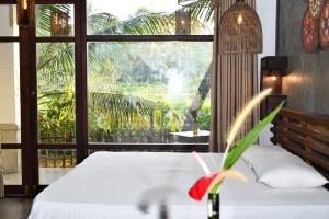a bedroom with a white bed and a large window at Guruwaththa Eco Lodge in Hikkaduwa