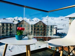 a table with a vase of flowers on a balcony at New Gudauri Panorama View Loft II in Gudauri