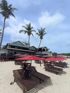 a group of tables and umbrellas on a beach at Seahorse Diver Guesthouse in Perhentian Islands