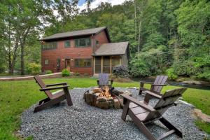 two chairs and a fire pit in front of a log cabin at Creeksong in Ellijay