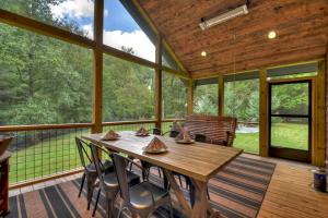 a large screened in porch with a wooden table and chairs at Creeksong in Ellijay