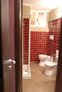 ein Badezimmer mit 2 WCs und roten Fliesen in der Unterkunft Suite&B in Scicli