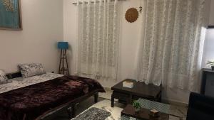 een slaapkamer met een bed en een raam met gordijnen bij Stay with Abhishek in Gwalior