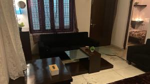 een woonkamer met een zwarte bank en een tafel bij Stay with Abhishek in Gwalior