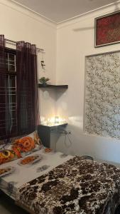een slaapkamer met een bed, een tafel en een raam bij Stay with Abhishek in Gwalior