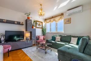 a living room with a green couch and a tv at Great view apartment in Zadar