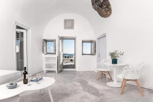 Sala de estar blanca con sillas blancas y mesa en Diamond Luxury Suites en Oia