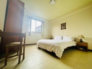 a bedroom with a bed and a chair and a window at Minimal Guest Houses in Addis Ababa