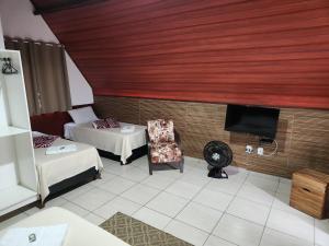 a room with two beds and a flat screen tv at Espaço Chalé Cereja in Cachoeira Paulista