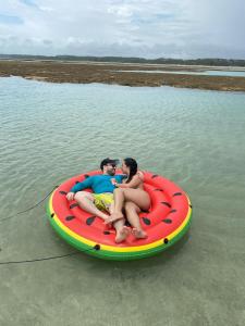 duas pessoas sentadas num barco insuflável na água em Pousada Caribe Milagrense em São Miguel dos Milagres