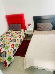 a bedroom with two beds and a red headboard at Acogedora casa llena de vida in San Luis Potosí
