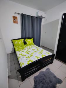 a bedroom with a bed with yellow flowers and a curtain at LES VAGUES BLEUES in Ilendé