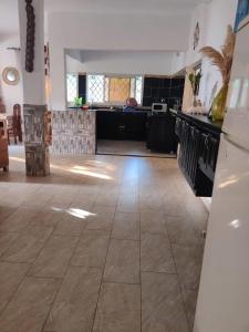 a large room with a tile floor and a kitchen at LES VAGUES BLEUES in Ilendé