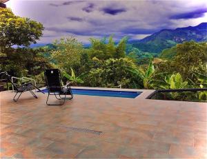 a pool with two chairs and a laptop on a patio at FINCA 100x100 PRIVADA- DESCANSO PLACENTERO - Sasaima in Sasaima