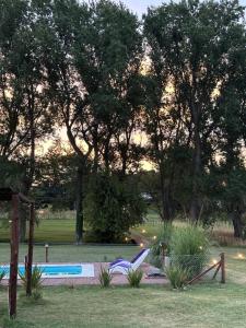 un patio trasero con piscina y algunos árboles en Cabaña Guanumby en Tandil