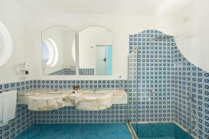 a bathroom with a blue and white tiled wall at Hotel Belair in Sorrento