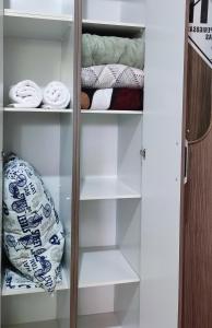 a closet with white shelves and a bed at uma casa na viagem in Três Cachoeiras